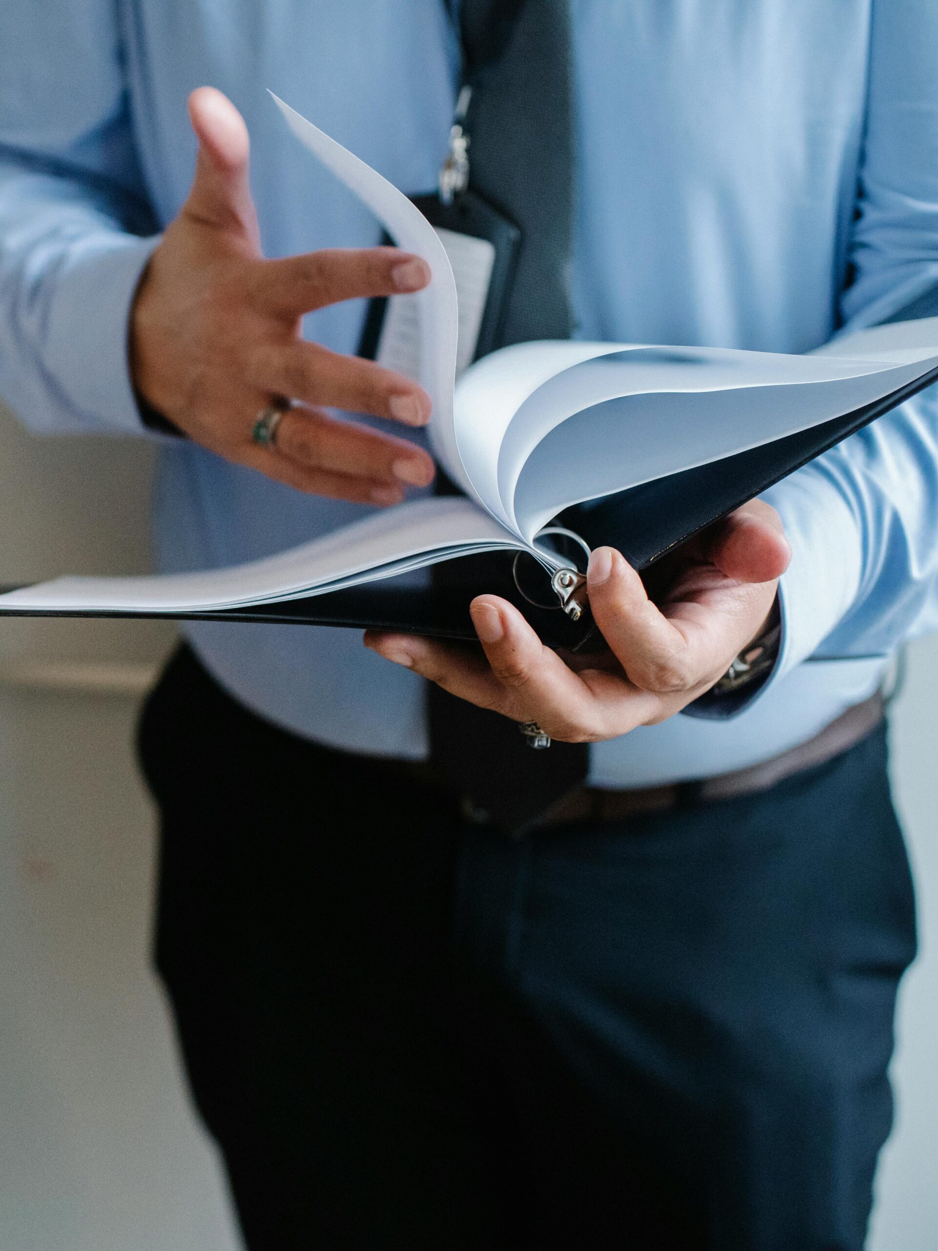 A business professional in a suit flips through documents indoors, emphasizing formal work settings.